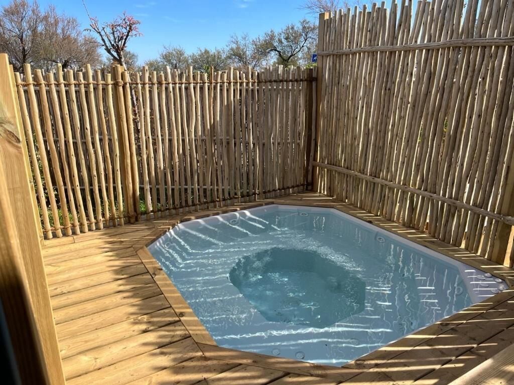 Un jacuzzi rodeado por una terraza de madera y una valla de bambú.