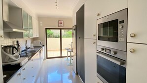 Una cocina moderna con horno empotrado, microondas y un amplio ventanal.