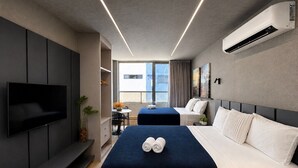 A modern hotel room with a flat-screen TV, two beds, a desk, and a large window. - Setai Yatch Garden  (João Pessoa)