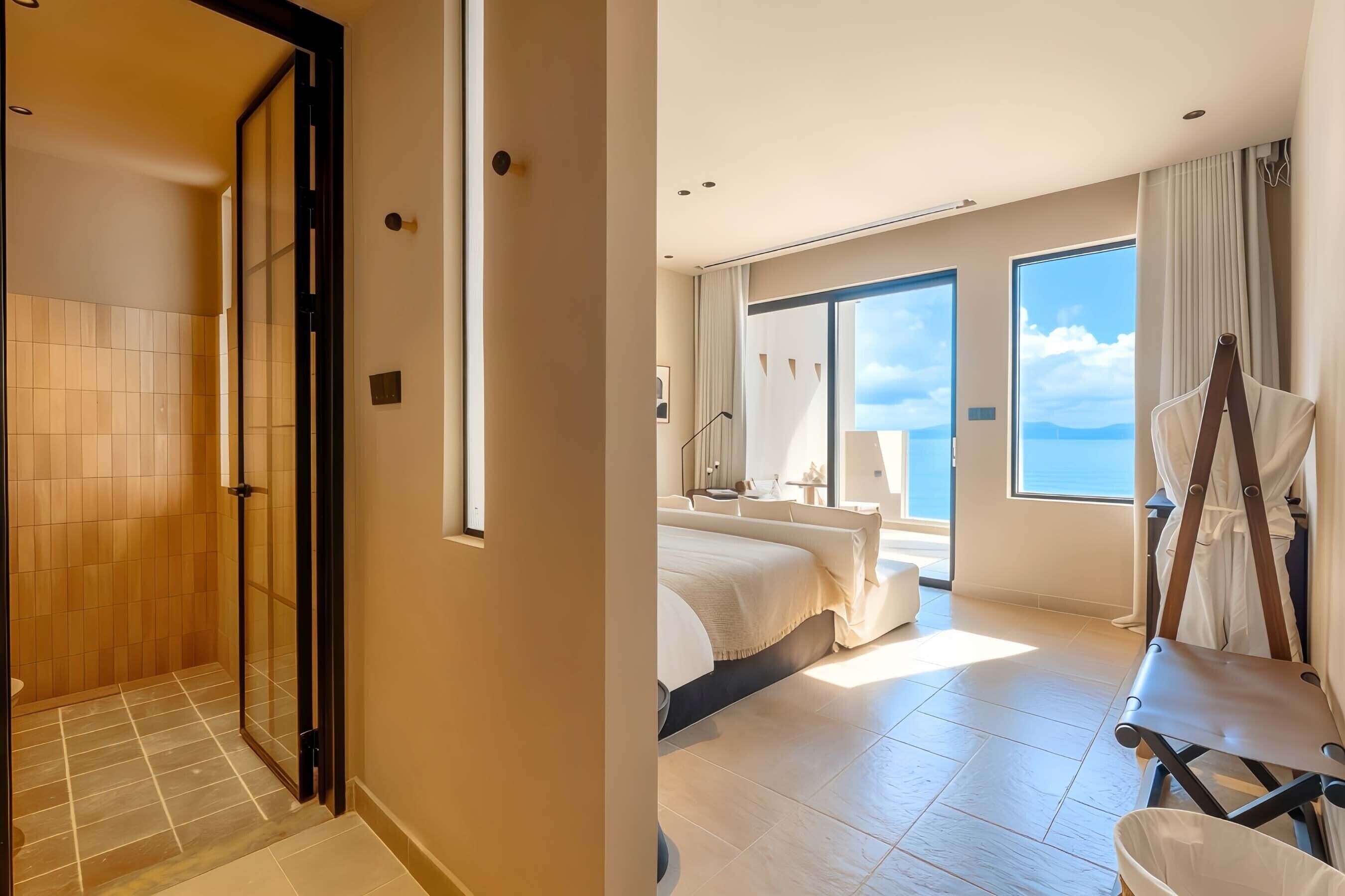 Ein Hotelzimmer mit Dusche, einem Bett, einem großen Fenster und Blick zum Himmel.