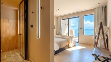 Ein Hotelzimmer mit Dusche, einem Bett, einem großen Fenster und Blick zum Himmel.