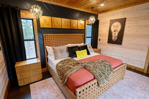 Ein Zimmer mit Holzwänden, einem Bett, einer Kommode und einer Wandleuchte.