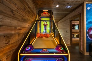 An indoor arcade game area with a basketball-themed game titled 'Super Hoops.' - Sleeps 52, Pond w/ Kayaks, Epic Game Room, Pool, UTV Access (Broken Bow)