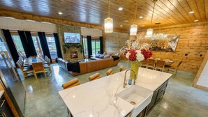 Una cocina moderna con encimera de mármol, lavavajillas integrado y comedor con mesa y sillas de madera.