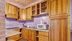 A kitchen with wooden cabinets, a microwave, a sink, and a window with a view. - Apartment 'Centenario Affittacamere' with Wi-Fi and Air Conditioning (Fara Novarese)