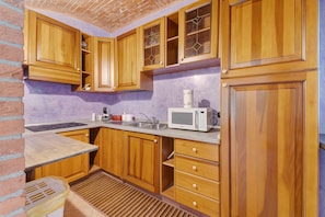 Une cuisine avec des meubles de rangement en bois, un four à micro-ondes, un évier et une fenêtre donnant sur un beau paysage.