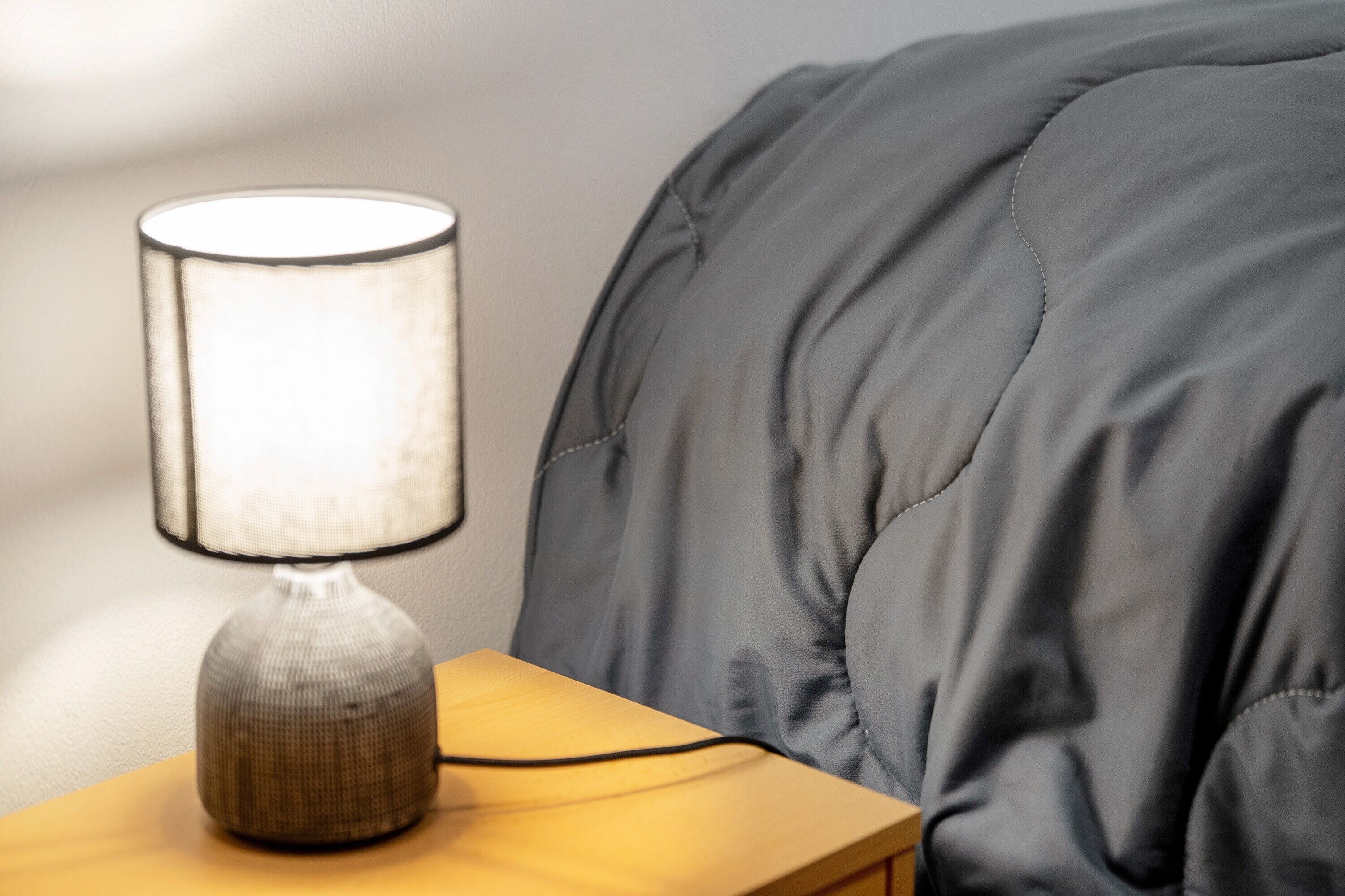 Ein Nachttisch mit Lampe, Kissen und einer Wand.