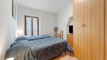 A bedroom with a bed, a wardrobe, a chair, a radiator, and a window.