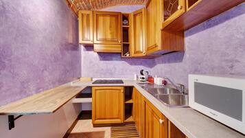 A compact kitchen with wooden cabinets, a built-in microwave, and a sink.