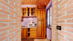 A kitchen with brick walls, wooden cabinets, a microwave, and a window. - Apartment 'Centenario Affittacamere' with Wi-Fi and Air Conditioning (Fara Novarese)