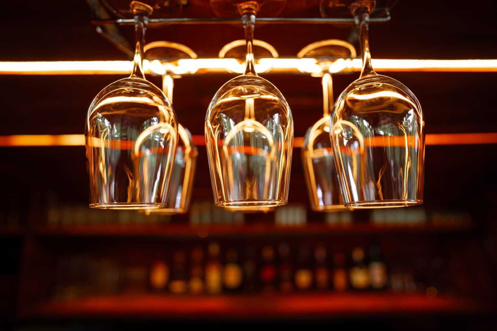 Zona de bar con copas colgando y un fondo borroso de estanterías.