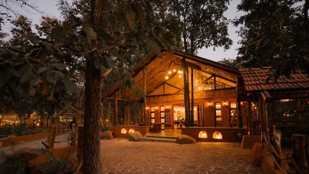 Un lodge rústico con entrada empedrada en piedra, vigas de madera e iluminación cálida.