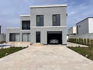 A modern two-story house with a garage, a swimming pool, and a well-maintained lawn.