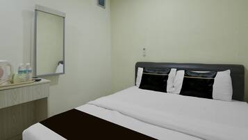 Una habitación de hotel con cama, mesita de noche, espejo y una ventana pequeña.