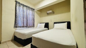 Una habitación pequeña con dos camas, una ventana con cortinas, un estante con toallas y un aire acondicionado de pared.