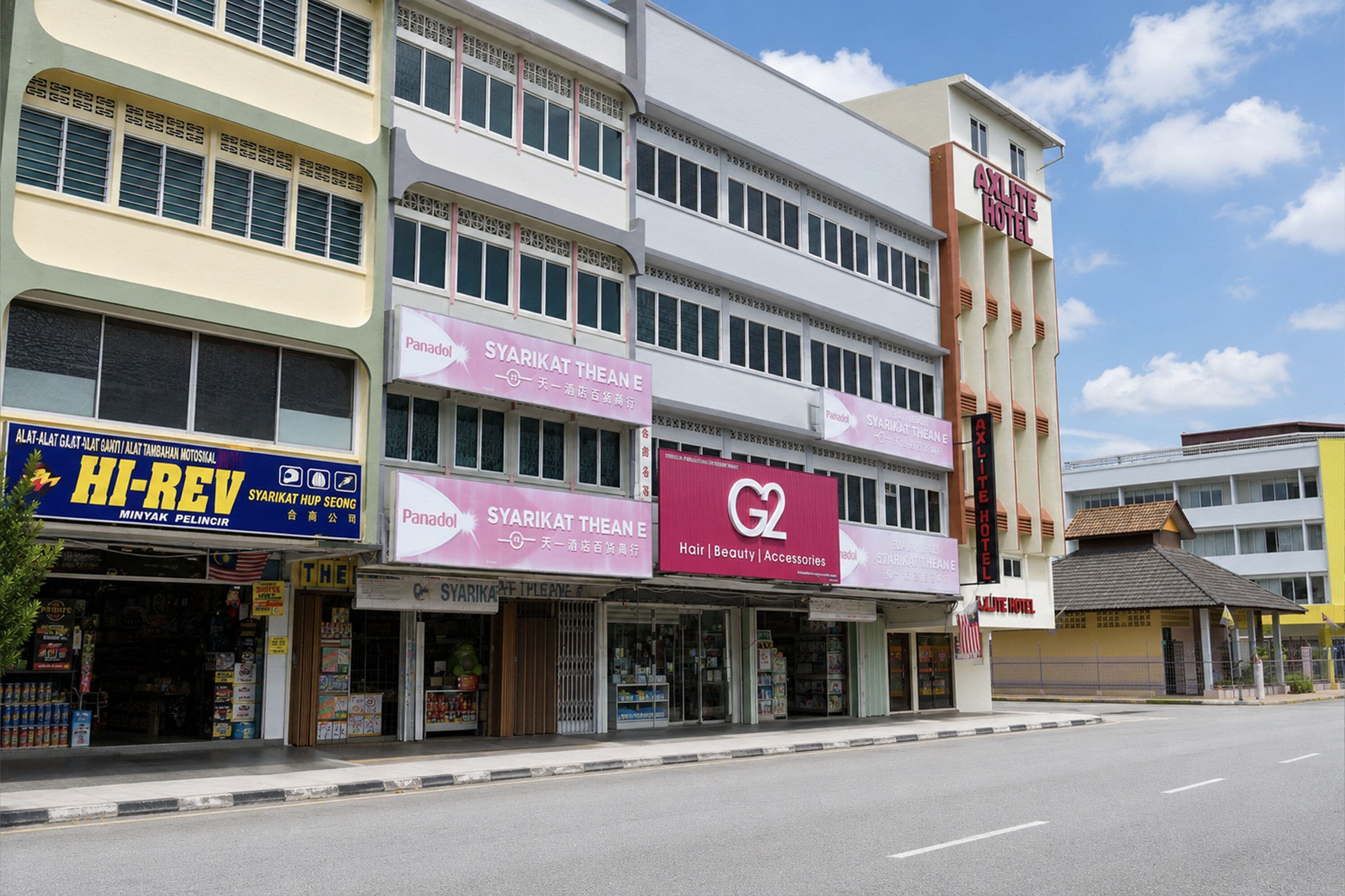 A multi-story building with signage for 'SYARIKAT THEAN E' and 'AXILITE HOTEL.'