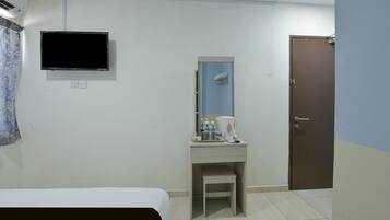 Una habitación de hotel con cama, escritorio con espejo, televisión, puerta y ducha.