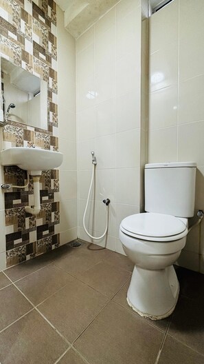 Un baño con inodoro blanco, lavamanos y ducha.