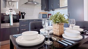 A modern kitchen with dark cabinetry, a microwave, and a dining area set with white plates, glasses, and a woven basket.