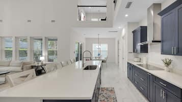 A modern kitchen with a central island, dark cabinetry, and a dining area with a sofa and table.