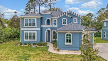 A two-story house with a curved front, multiple windows, and a well-maintained lawn.