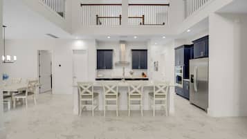 A spacious kitchen with a central island, dark cabinets, and a stainless steel refrigerator.