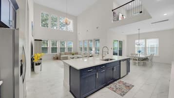 A spacious kitchen with a large island, a dining area with a table and chairs, and a living room with a sofa and a coffee table.