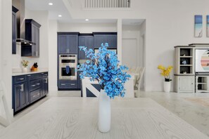 Eine moderne Küche mit dunklen Schränken, einer weißen Vase mit blauen Blumen und einem Essbereich mit Holztisch.