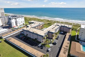 Een hotel met meerdere verdiepingen, een parkeerplaats, uitzicht op het strand en een zwembad.
