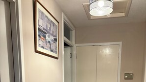 A hallway with a wooden bench, a framed picture on the wall, and a white closet with a door.