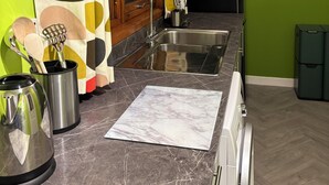 A kitchen with a double sink, wooden cabinets, a stainless steel refrigerator, and a green wall.