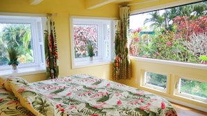 Une chambre avec un lit, de grandes fenêtres et une vue sur la verdure.