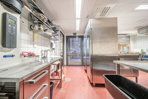 Eine gewerbliche Küche mit Edelstahlgeräten, einer digitalen Bedienkonsole und einem roten Boden.