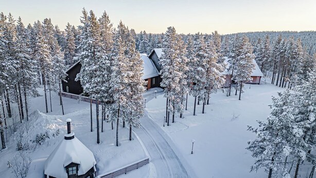 A snow-covered landscape with multiple cabins surrounded by trees.