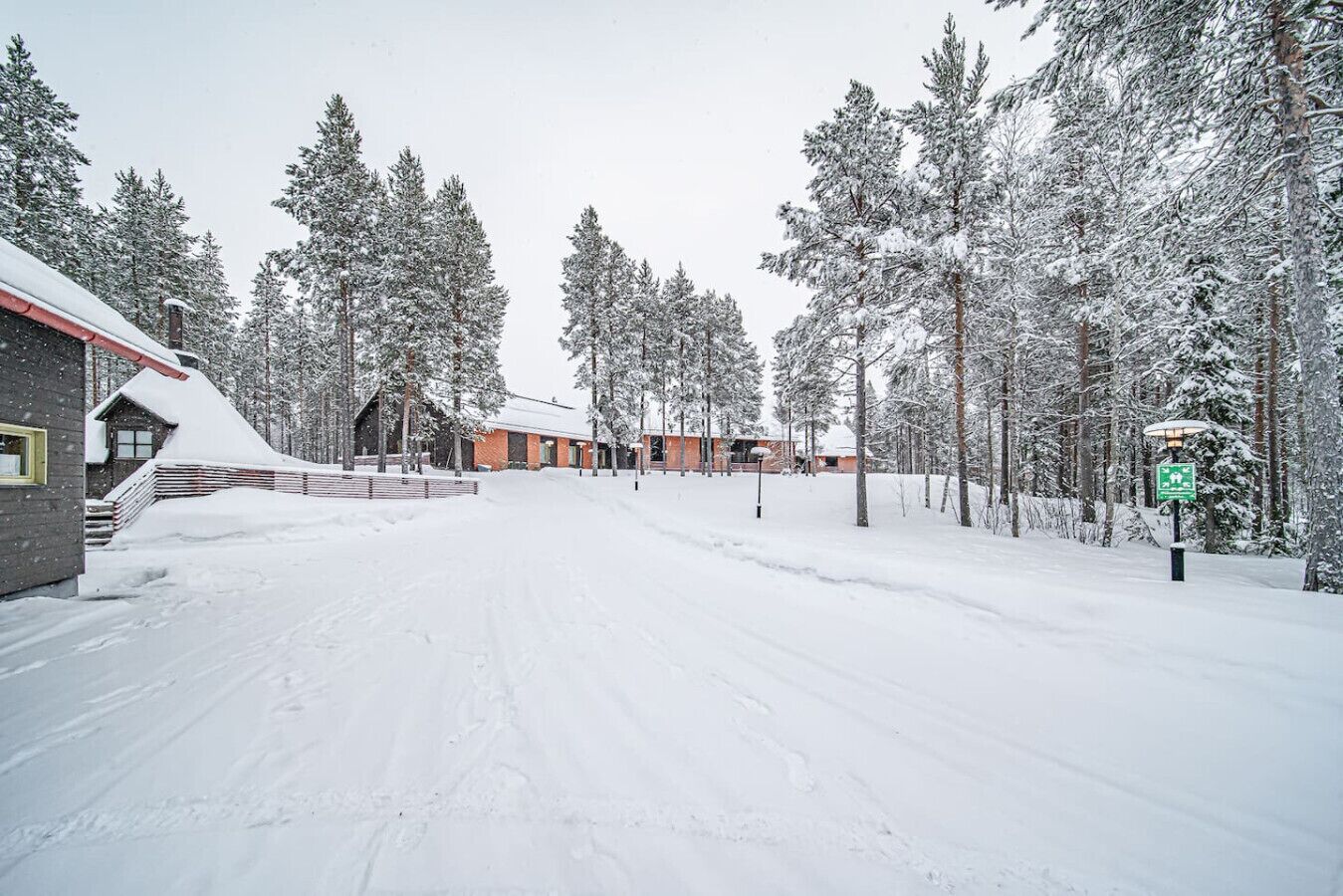 Lumipeitteinen katu, jonka varrella on rakennuksia ja puita.