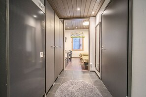 Un pasillo estrecho con un tapete, que conduce a una habitación con cama y ventana.
