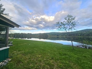 A lakeside view with a grassy area, a small structure, and a tree. - Brant Lake-Guest House | 8 Beds | Near Gore (Brant Lake)