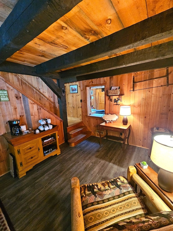 Un intérieur rustique en bois, avec un escalier, un bureau en bois, une lampe et un coin café.
