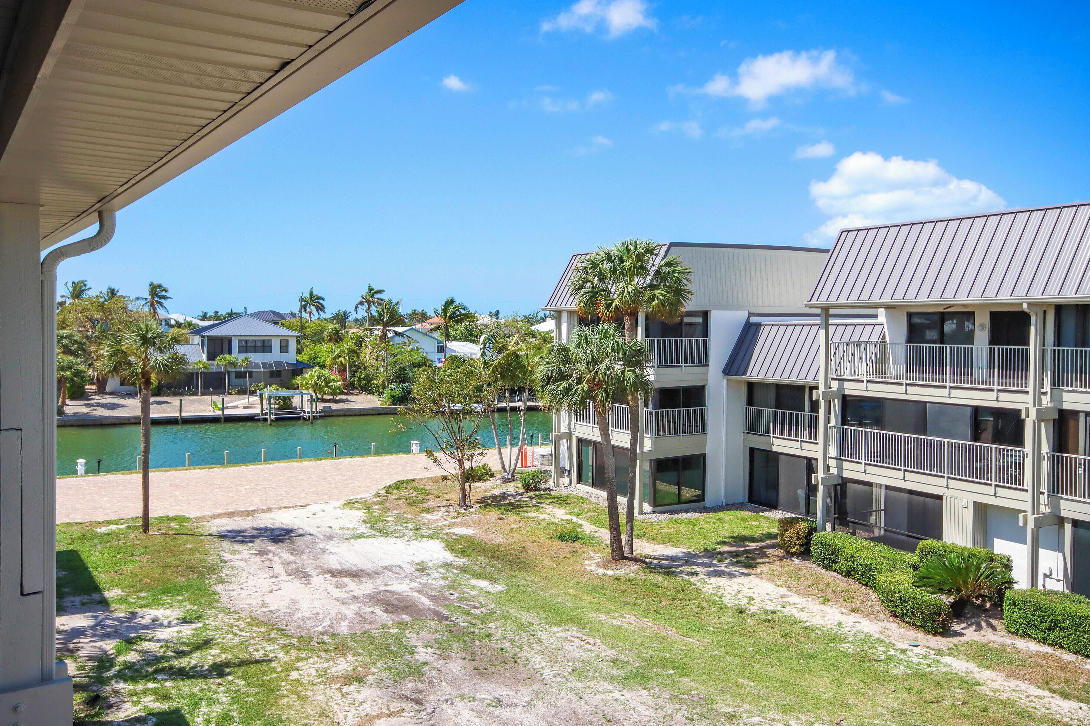A multi-story building with balconies, a pool, and palm trees.