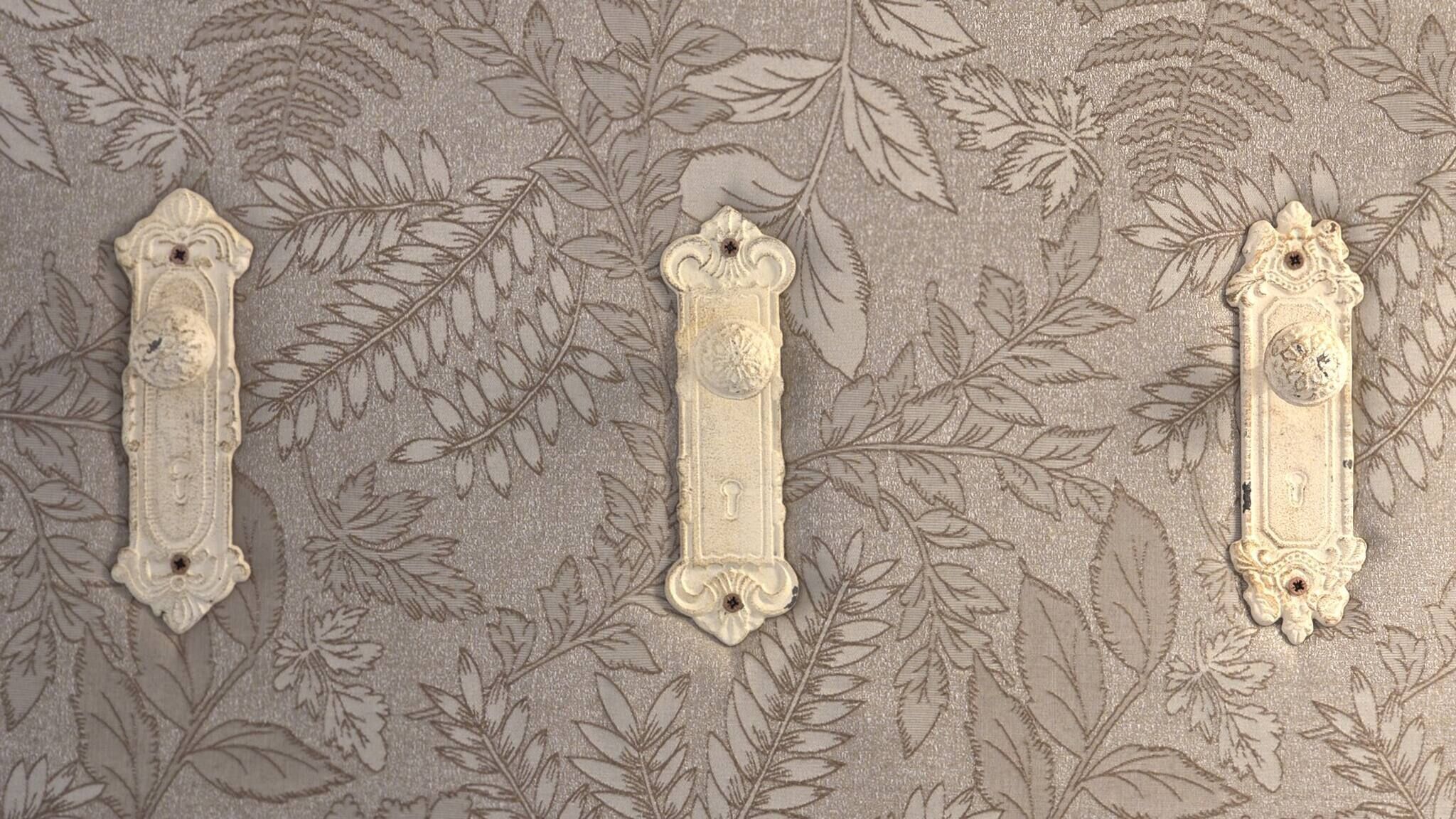 Three ornate metal handles on a textured wall with a leaf pattern.