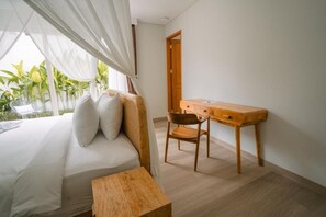 Un dormitorio con cama, un escritorio de madera, una silla y una mesita.