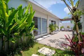 A modern house with a patio, large windows, and lush greenery. - Nyuh Lengkong Beachfront Villa (Tabanan)