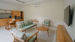Un salon moderne avec un canapé, des fauteuils, une table basse et un téléviseur.