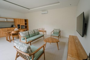Una sala de estar moderna con un sofá, sillas, una mesa de centro y un televisor.
