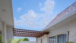 A patio with a wooden deck, outdoor furniture, and potted plants. - Nyuh Lengkong Beachfront Villa (Tabanan)