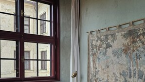 Un dormitorio con cama, un radiador, una ventana con cortinas y un tapiz en la pared.