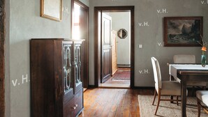 Una habitación con un armario de madera, una mesa de comedor con sillas, un cuadro en la pared y una puerta que da a otra habitación.