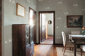 A room with a wooden cabinet, a dining table with chairs, a painting on the wall, and a door leading to another room. - Schloss Schmarsow (Kruckow)