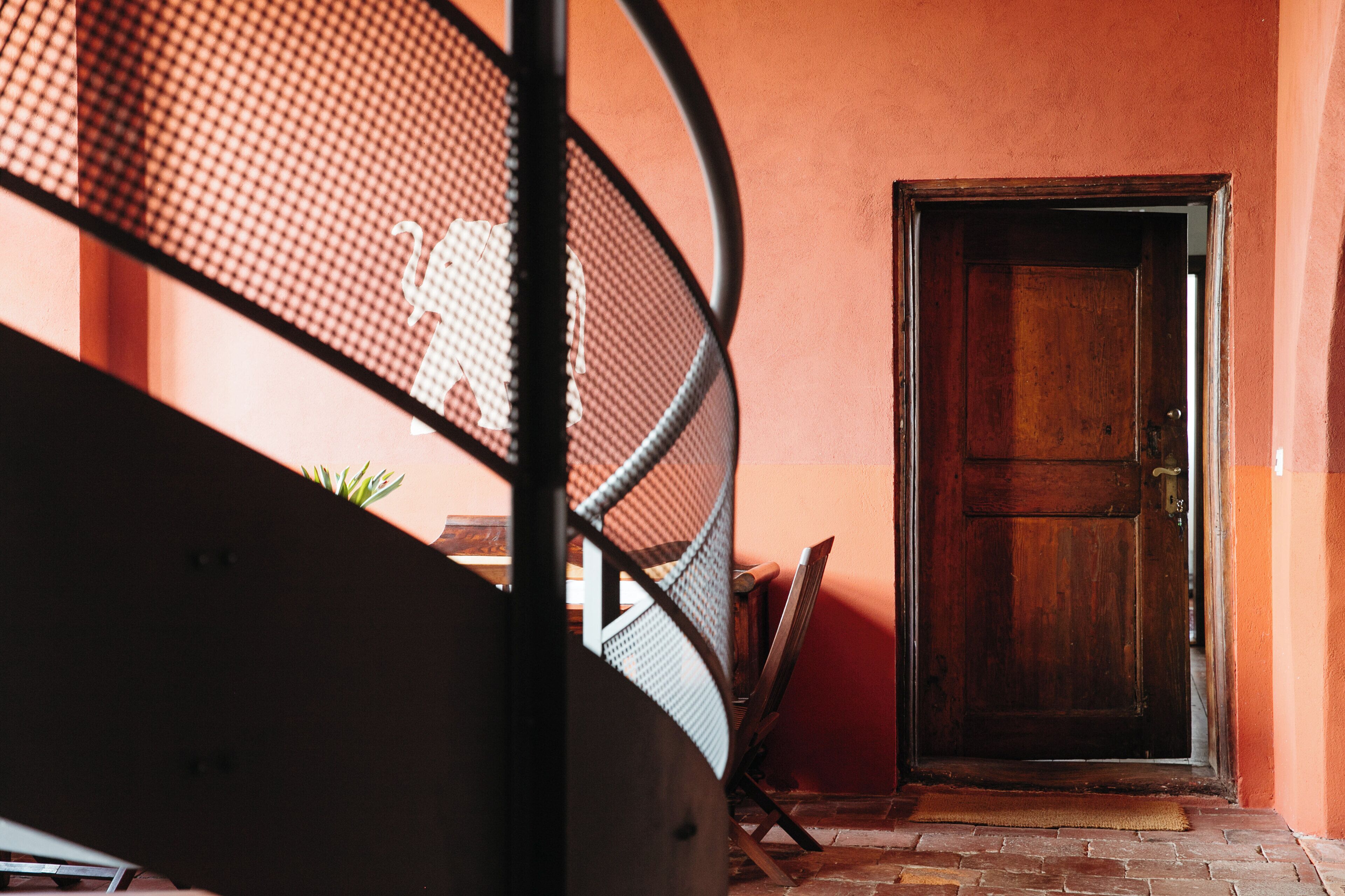 Una escalera en espiral que conduce a una habitación con una puerta de madera y una pared roja.