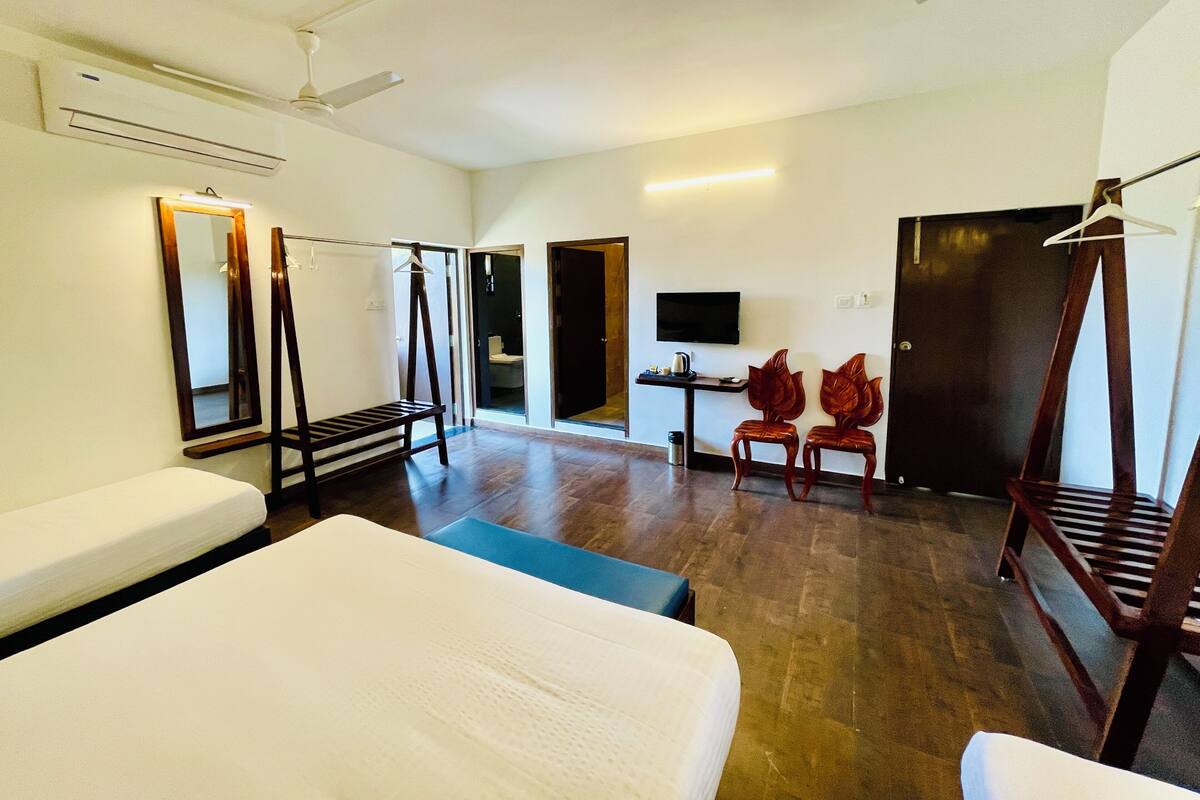 A hotel room with a bed, a desk with a TV, a mirror, and a wardrobe.